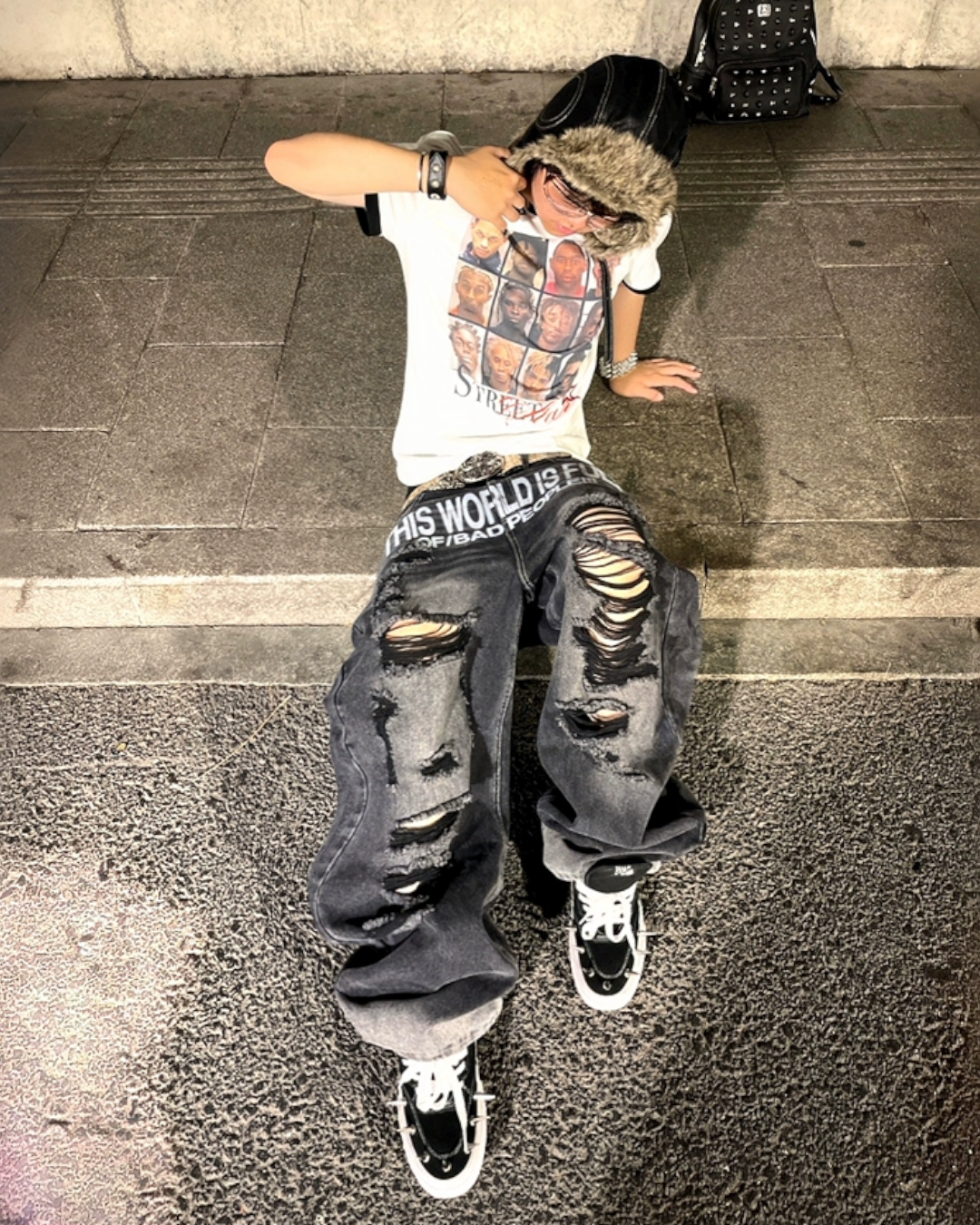 Person wearing a SWAG white t-shirt with graphic design and ripped jeans on a street.