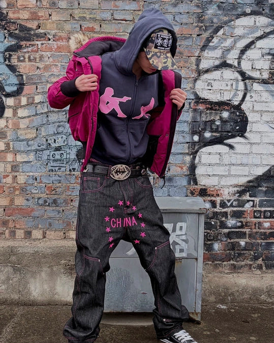 Dark zip hoodie with pink dancing figure graphic, worn with hood and front pocket