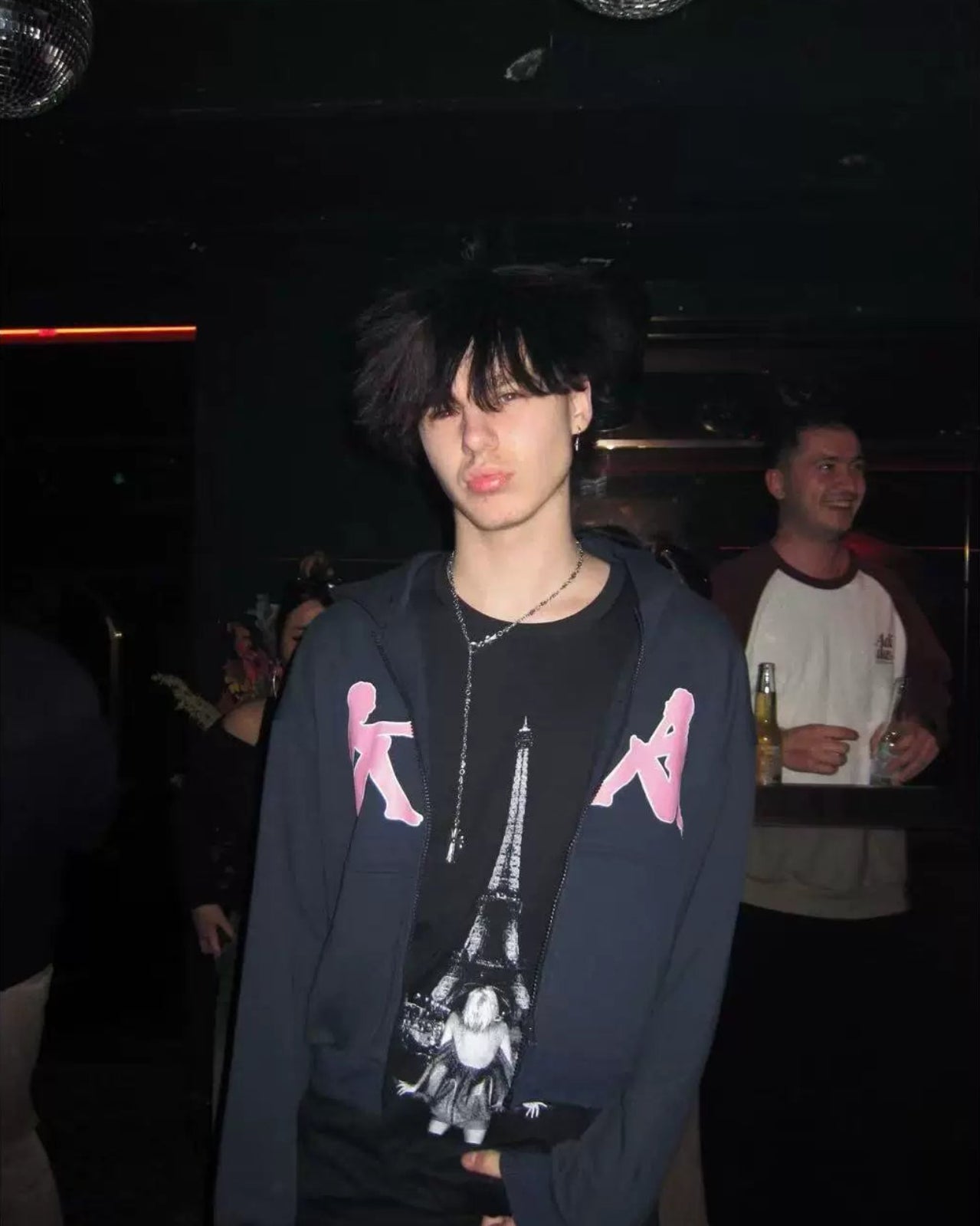 Dark zip hoodie with pink dancing figure graphic on front, model wearing the hood