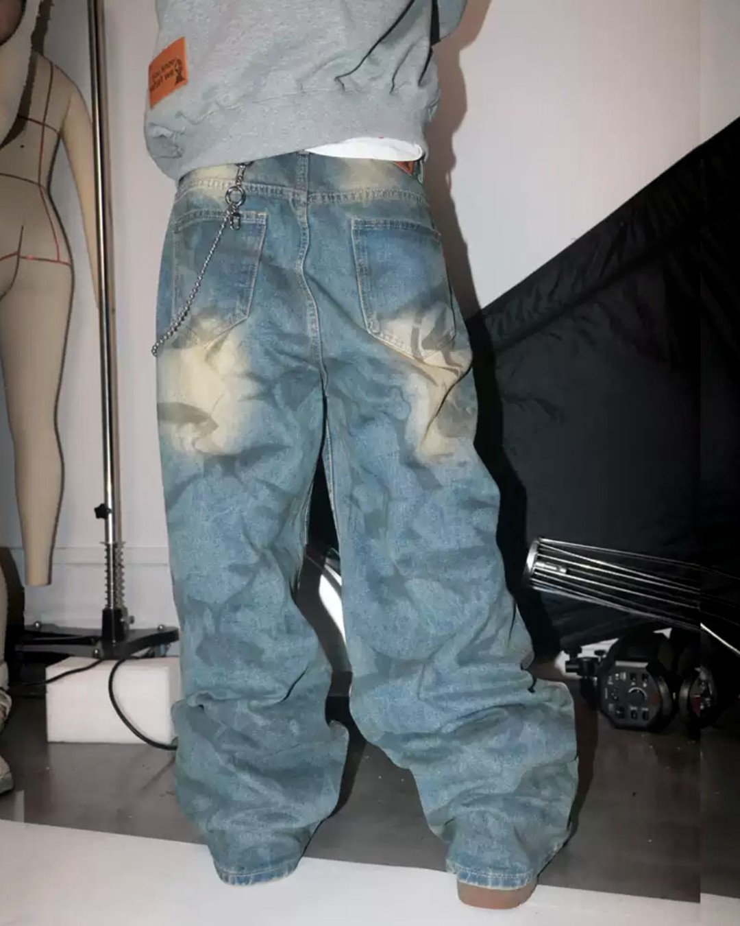 Faded blue baggy jeans with washed creases, distressed light patches, relaxed fit