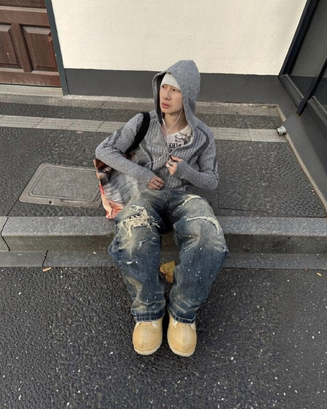 Baggy blue denim jeans with heavy knee rips, lighter patches, and stitched seams