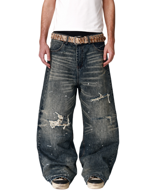 Baggy dark blue denim jeans with patched rips and worn knees, belt loops